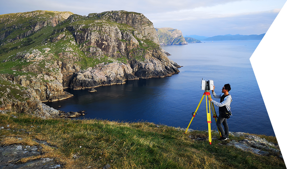 Lidar Scanning on a cliff next to the sea Clear Angle crew member with a Leica P40 on top of a cliff with the ocean in the background, capturing a Lidar scan of the environment