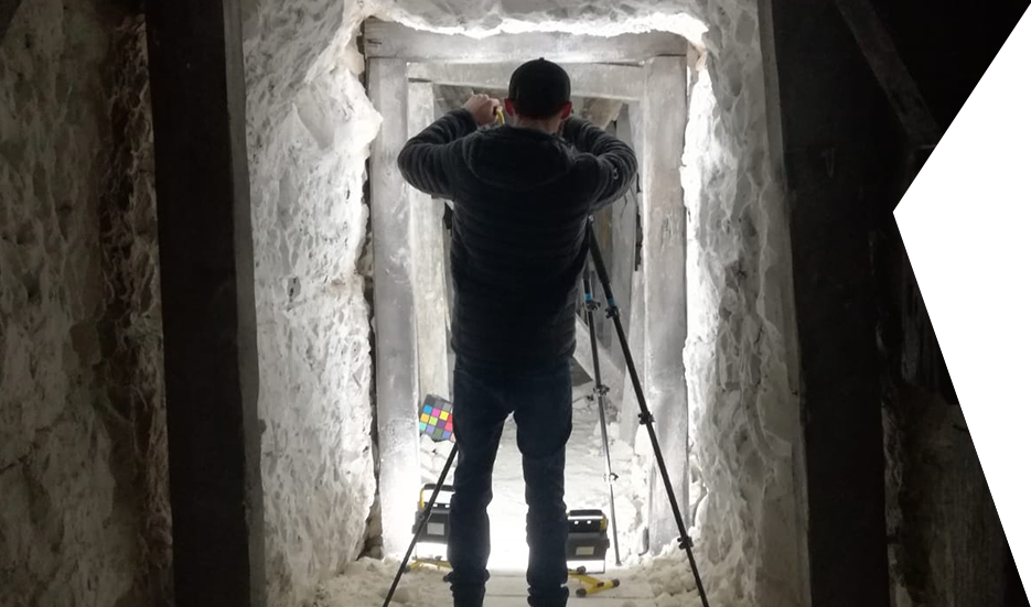 Clear Angle crewmember taking a photograph in a rough, white stone passage Clear Angle crewmember taking a photograph in a rough, white stone passage