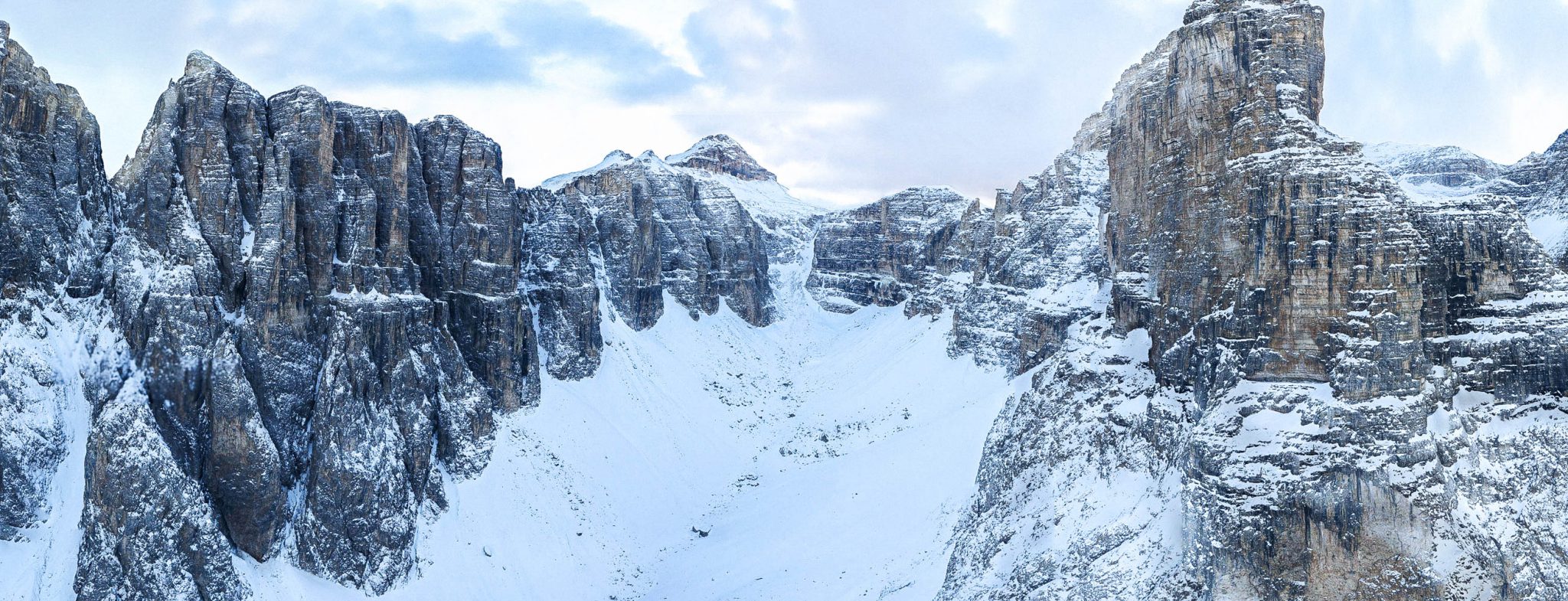 Image of a snowy valley with steep, rocky cliffs on either side, taken from a helicopter during an aerial 3D scan of the environment