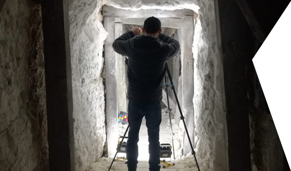 Clear Angle crewmember taking a photograph in a rough, white stone passage